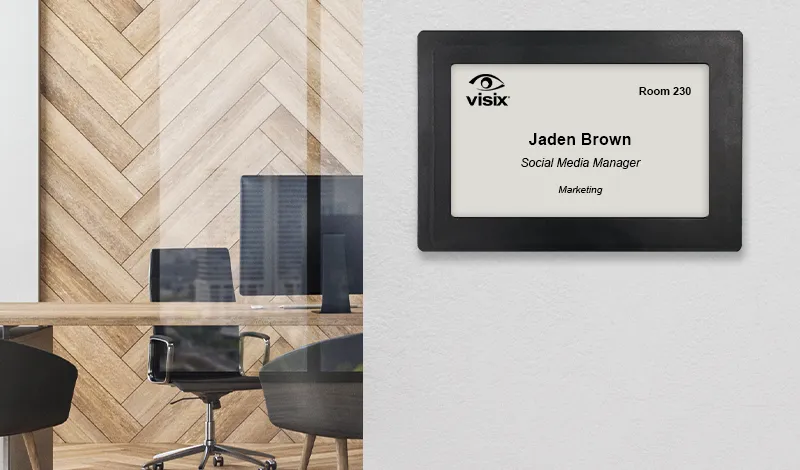 picture of E Ink sign used as a digital name plate outside of an office with a desk, chair and monitor