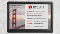 ePaper room sign with law office branding showing meeting schedule and logo on Golden Gate Bridge graphic background