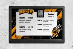 ePaper room sign with black and yellow hornets graphics and branding showing events schedule, QR tag and logo