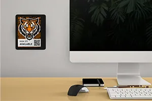 ePaper desk sign with desk reservation QR code in white block with tiger head graphic mounted on wall behind desk