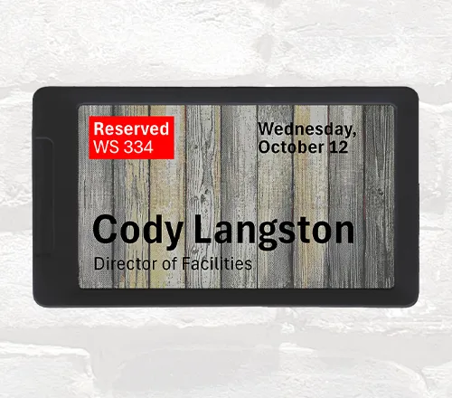 ePaper desk sign with wood panel background graphic showing current workspace reservation in red