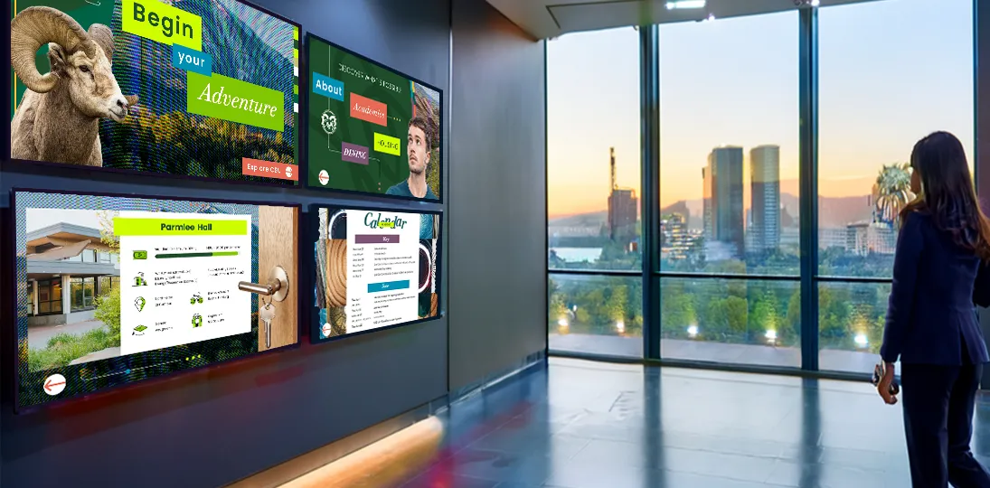 photo of employee looking at four digital signage displays with graphics and announcements